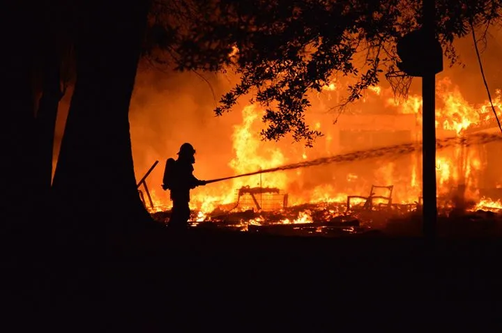 Firefighter silhouetted against fully involved structure fire at night