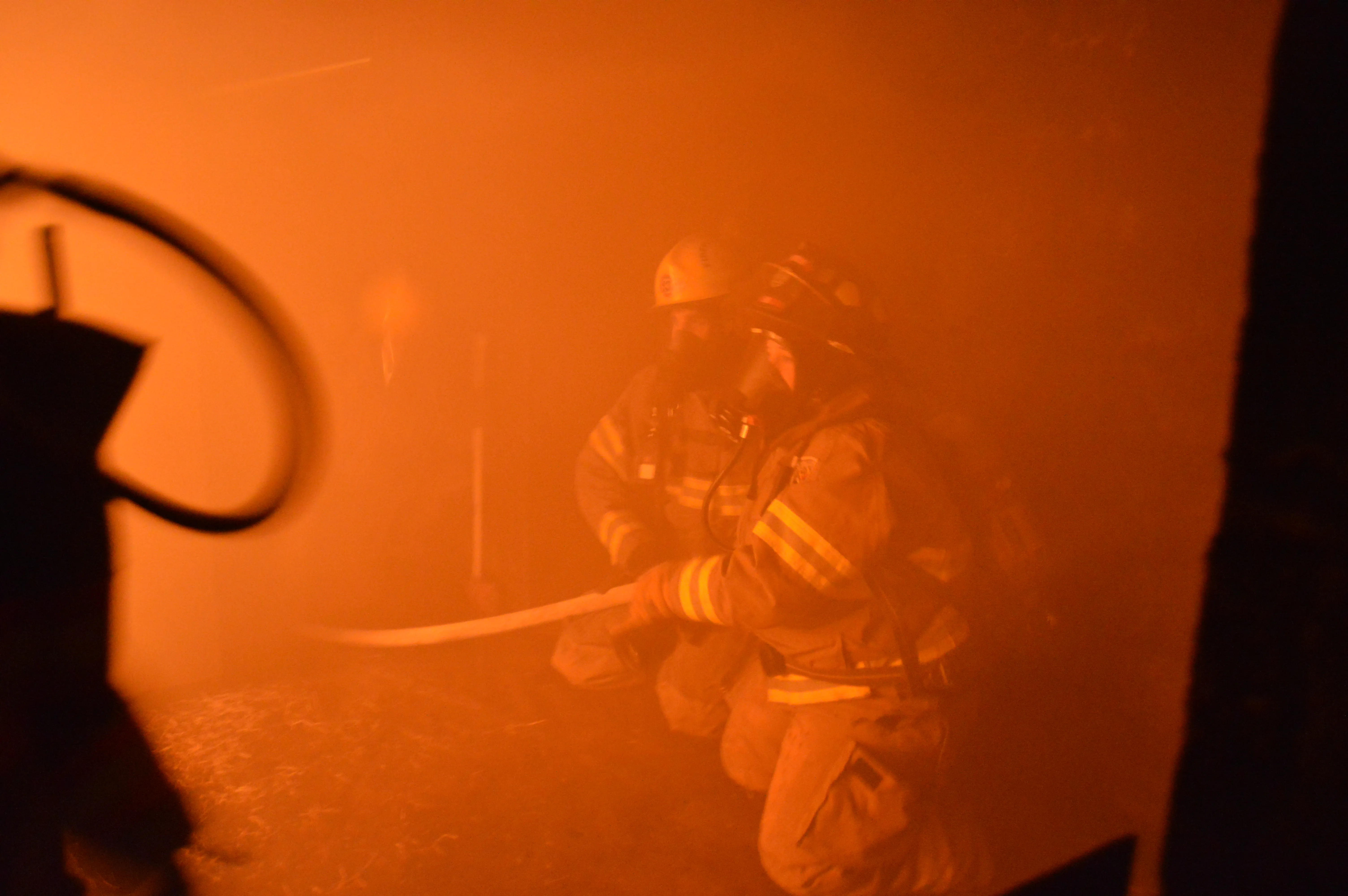 Firefighter advancing hoseline through heavy smoke